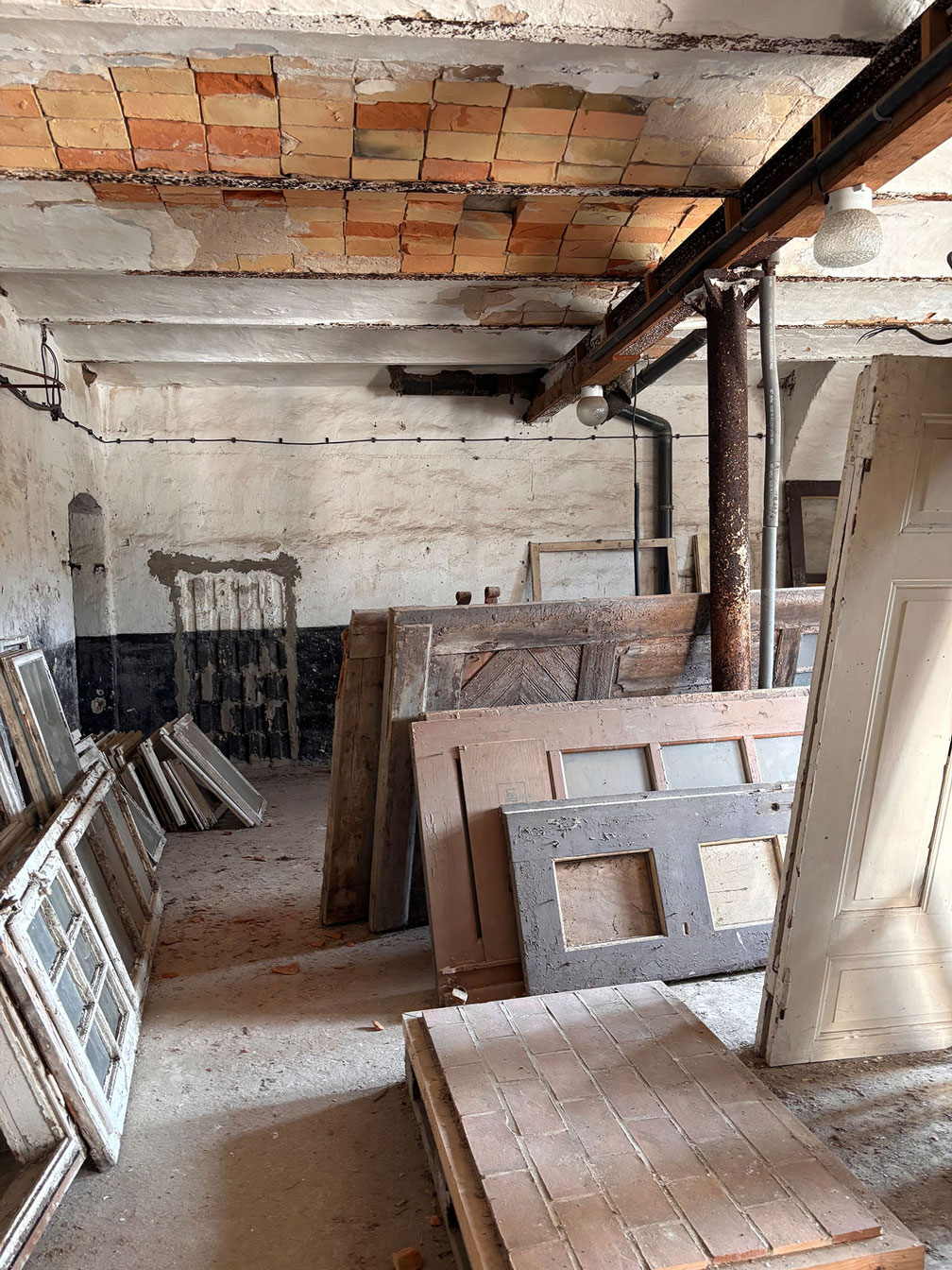 Innenansicht des Alten Pferdestalls auf dem Hermannshof in Rheinsberg mit Preußischer Kappendecke und gelagerten historischen Holztüren und Fensterrahmen
